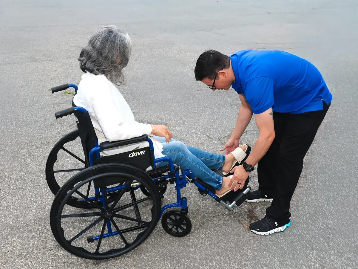 A MoveMe Medical driver adjusting the footrests of a rider's wheelchair