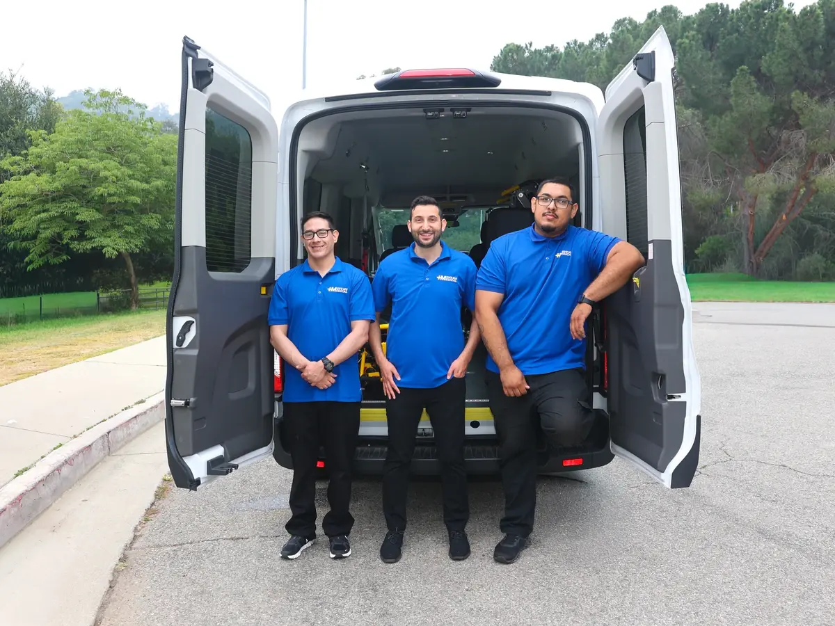MoveMe Medical team members standing at the open rear doors of a transport van