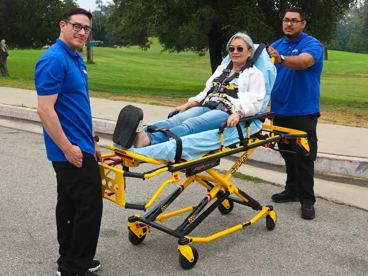 MoveMe Medical team members with a rider reclined on a Stryker gurney