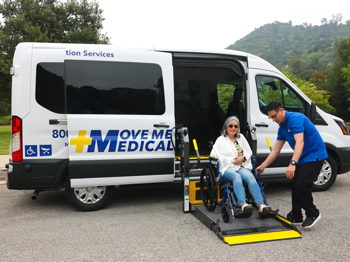 A rider in a wheelchair boarding an ADA-compliant van on the lift with driver assistance